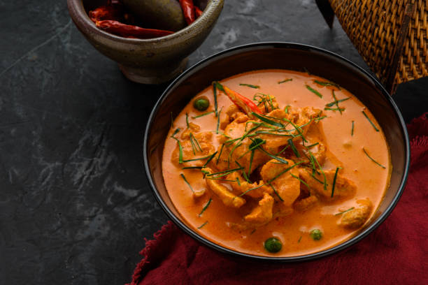 istock Thai red chicken curry on wooden table with ingredients decorate around. 812488312