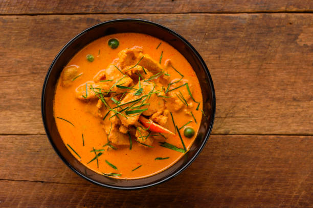 istock Thai red chicken curry on wooden table with ingredients decorate around. 812488322