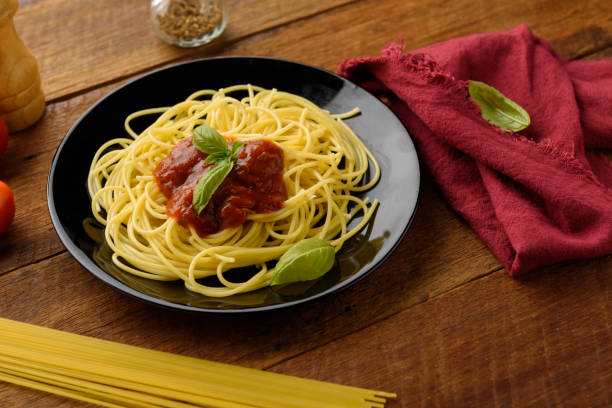 istock Spaghetti with tomato sauce and their ingredients around on wooden table. 812494776