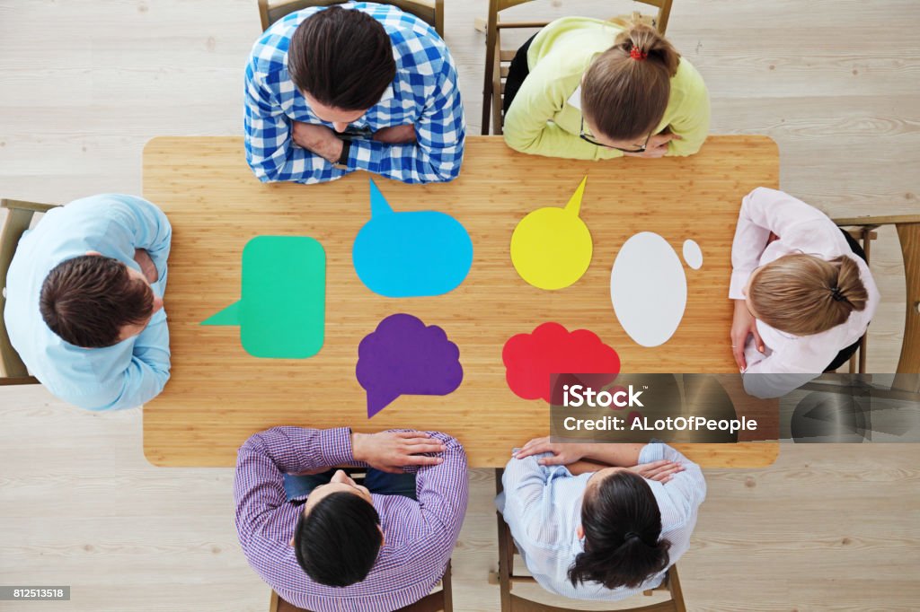 Business team and dialog boxes Team of business people in casual clothes sitting around the table with paper dialog boxes, discussing opinion concept Communication Stock Photo
