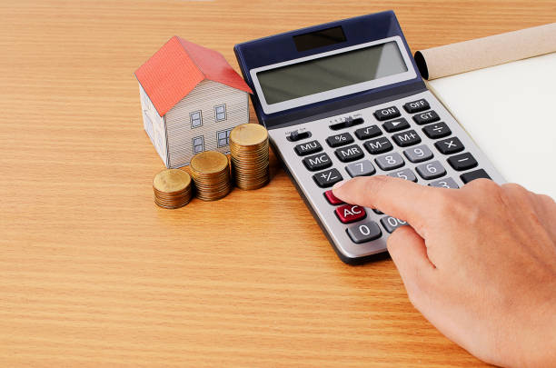 istock Hand on calculator with coins stack and paper house for mortgage loans concept 812523934