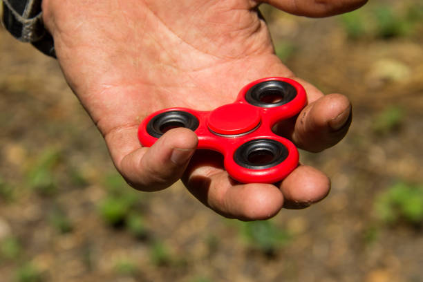 istock Man playing with fidget spinner stress relieving toy outdoor 812555688
