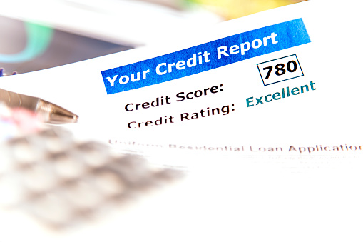 Know your credit score!  Credit report documents including score and rating along with a calculator, pen and residential loan application on desk.  Other books, documents in background.
