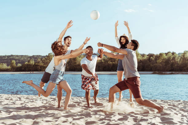 istock young smiling friends playing beach volleyball on riverside at daytime 812588532