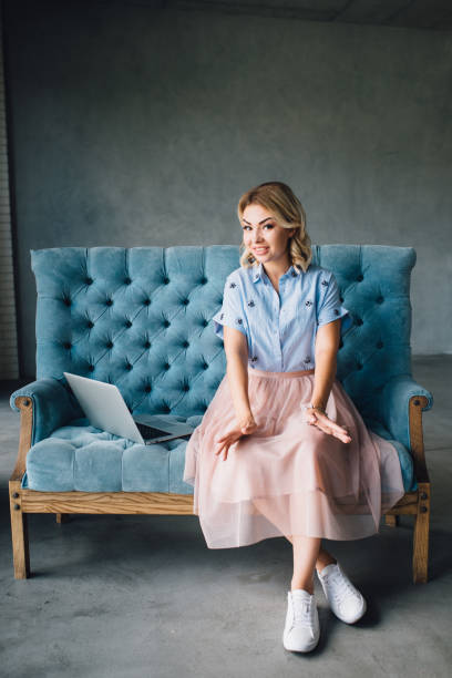 istock Happy woman sitting on couch using her laptop 812622542