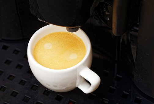 Closeup white cup with espresso preparation in coffee machine