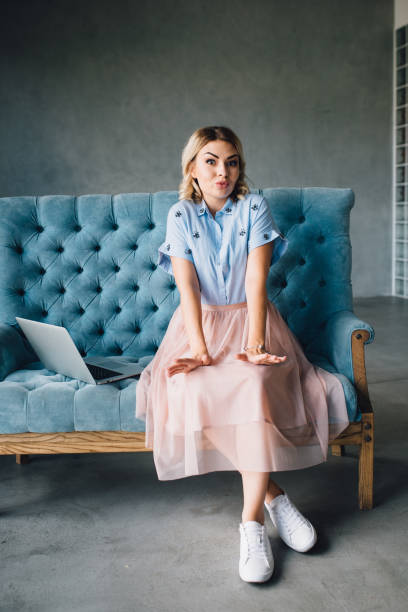 istock Happy woman sitting on couch using her laptop 812632548
