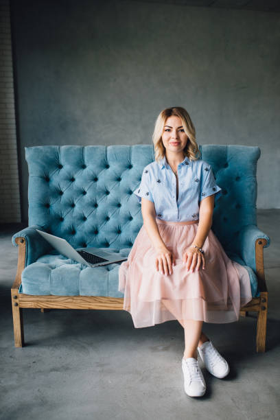 istock Happy woman sitting on couch using her laptop 812633694