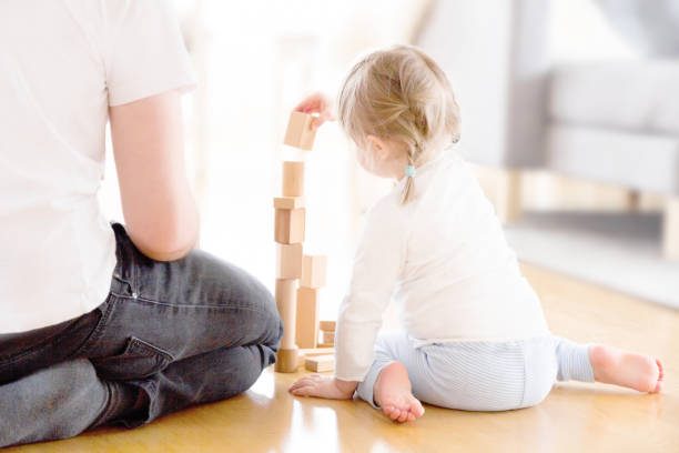 urocza dziewczyna bawi się drewnianymi blokami na podłodze z ojcem - wood toy block tower zdjęcia i obrazy z banku zdjęć