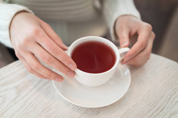 istock Female hands holding a white cup of tea standing on the table 812661298