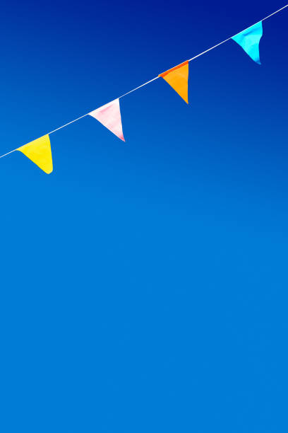 Four colorful party flags blowing in the wind against blue sky.