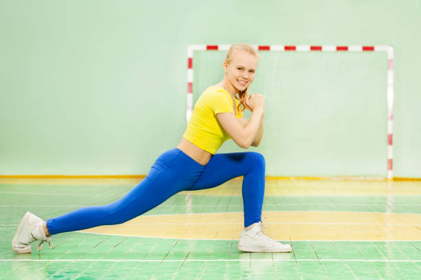 beautiful blond girl performing the forward lunge - bending knees imagens e fotografias de stock