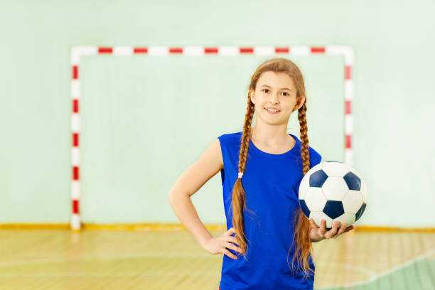 nastoletnia dziewczyna z piłką nożną w szkolnej siłowni - playing field kids soccer goalie soccer player zdjęcia i obrazy z banku zdjęć
