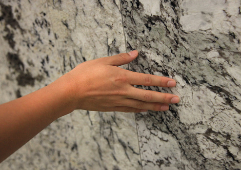 Hand gently touching piece of granite stone.
