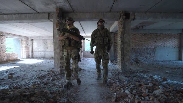 istock Men with guns walking among ruins 812757186