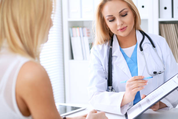 istock Doctor and  patient  discussing something while phisician pointing into medical history form at clipboard 812760086