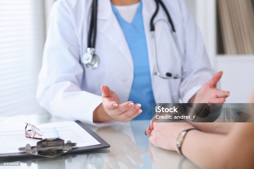 Gros plan d’un médecin et son patient mains discuté d’un sujet tout en étant assis à la table - Photo de Docteur libre de droits