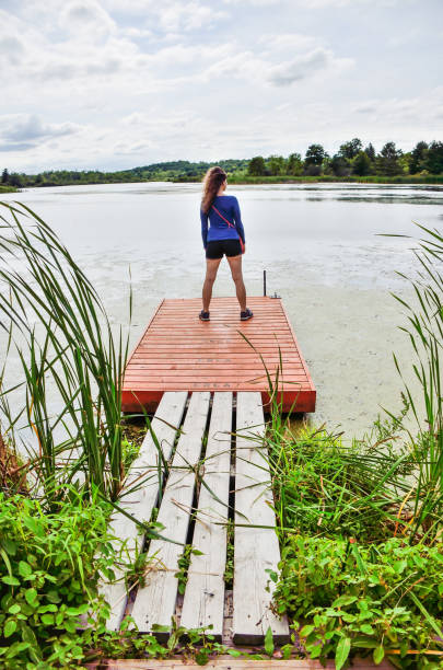 istock Young woman standing on small dock overlooking lake 812763406
