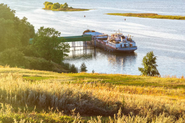 Loading grain from the elevator to the barge on the river in the summer at sunset on a clear day