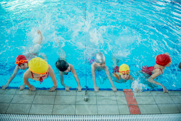 istock Instructor and group of children doing exercises near a swimming pool 812782256