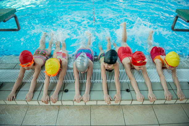 istock Instructor and group of children doing exercises near a swimming pool 812782570
