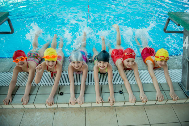 istock Instructor and group of children doing exercises near a swimming pool 812784792