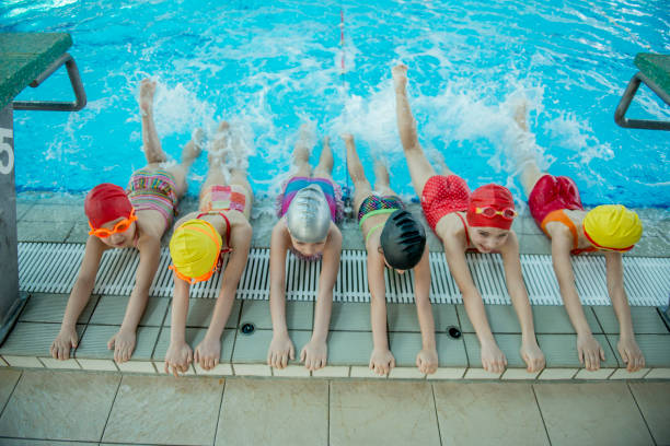 istock Instructor and group of children doing exercises near a swimming pool 812784992