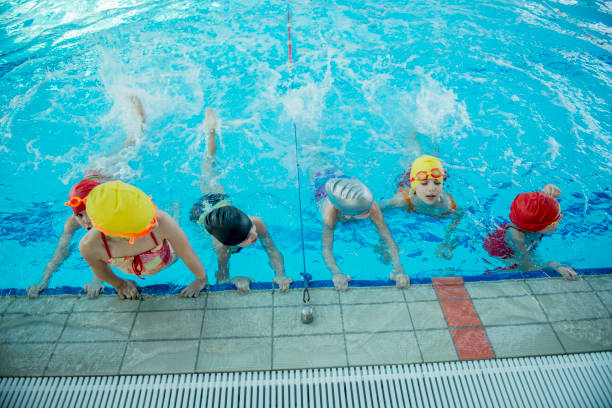 istock Instructor and group of children doing exercises near a swimming pool 812785114