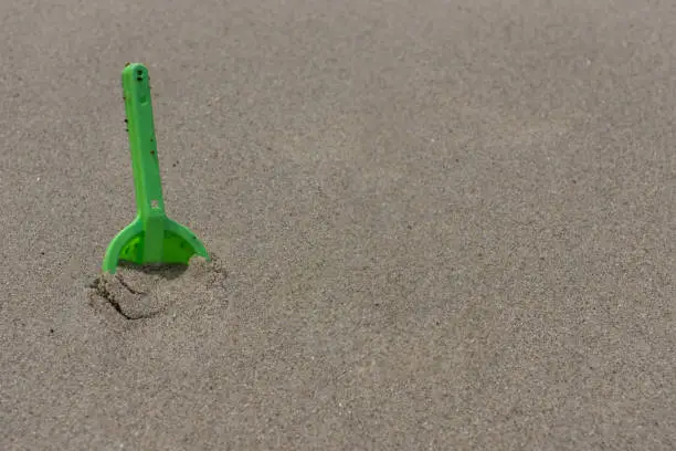 Photo of Dirty Green Shovel Digging in Wet Sand