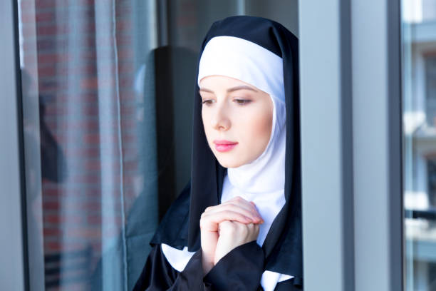joven monja triste junto a la ventana - nun praying clergy women fotografías e imágenes de stock