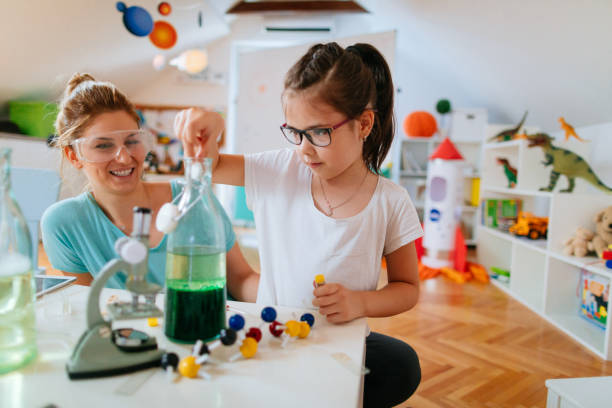 mädchen und ihre mutter dabei wissenschaftliche experiment - child playroom parent indoors stock-fotos und bilder