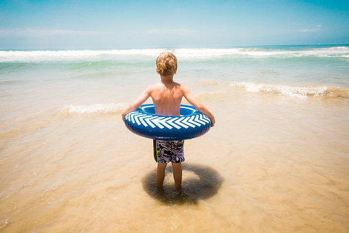 Young Boy Having Fun In The Ocean on a tube.