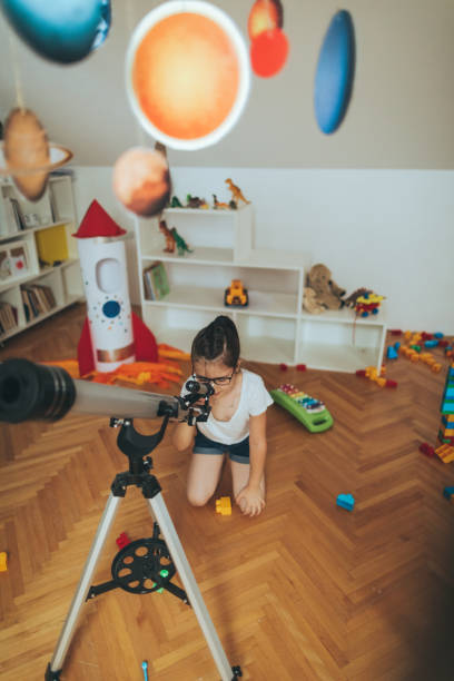 istock Little girl using a telescope 812828102