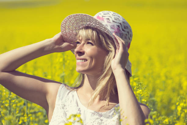 istock Young woman with a hat enjoying summer on the rape field 812828924