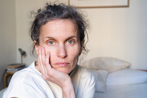 Portrait of despondent middle aged woman in bedroom (selective focus)