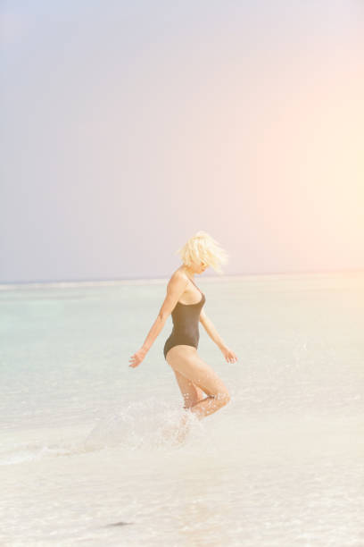 istock Woman in bikini running through water on sandy beach, Maldives 812845332