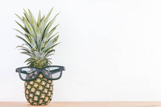istock Fresh pineapple with sunglasses on wooden table 812852838