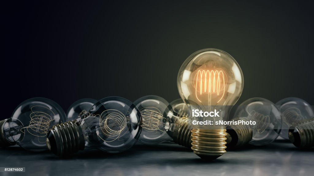 Multiple 3D Illustrated Incandescent Light Bulbs on a Reflective Surface Multiple incandescent light bulbs on a reflective surface and dark background.  One hero bulb illuminated, standing out from the rest.  Great for conveying a big idea or unique business thoughts.  3D illustration. Standing Out From The Crowd Stock Photo