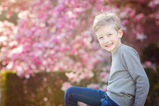 kid at spring beautiful smiling boy enjoying spring time with blooming magnolia tree in the background magnolia white flower large stock pictures, royalty-free photos & images