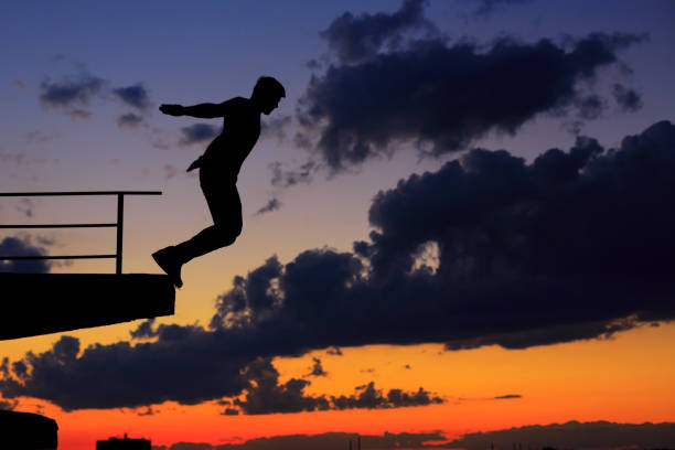 istock Man is jumping from edge of roof. Clouds and sunset 812894270