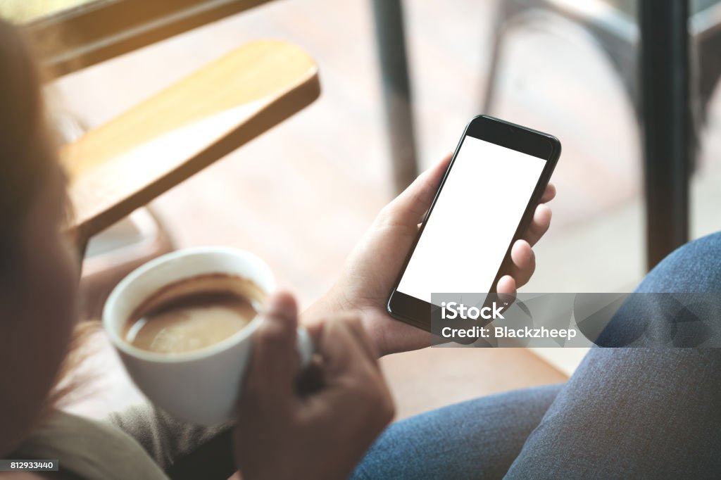 selective focus on woman hand holding phone sitting in coffee shop Coffee - Drink Stock Photo