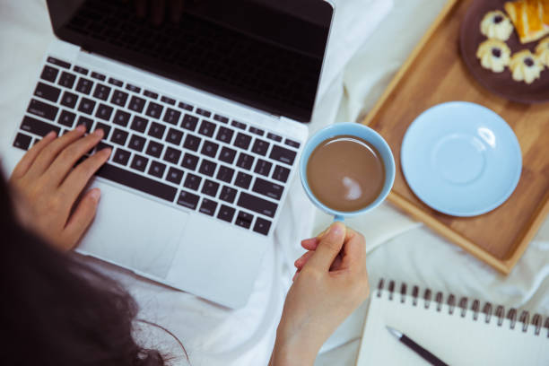 istock Woman drinking coffee with laptop in bed 812933908