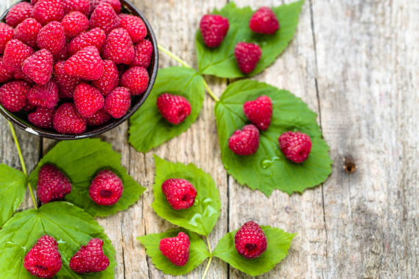 istock Freshly harvested raspberry fruits in a bowl on wooden table 812945198