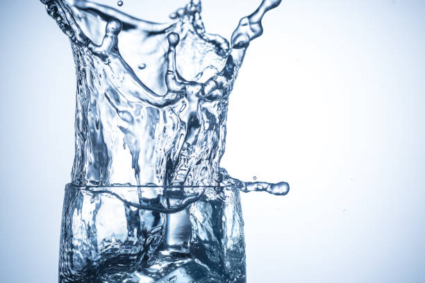 istock Ice cubes falling in glass with water splashes close up 812954840
