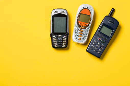 Old mobile phones on yellow background with free space for your text.