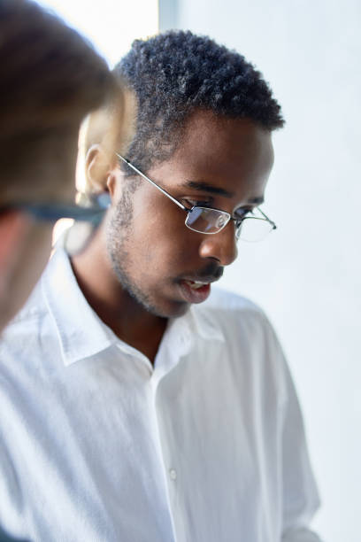 istock Young African Businessman Discussing Work with Colleague in Office 812970448