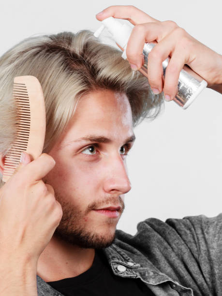 istock Man applying spray cosmetic to his hair 812973976