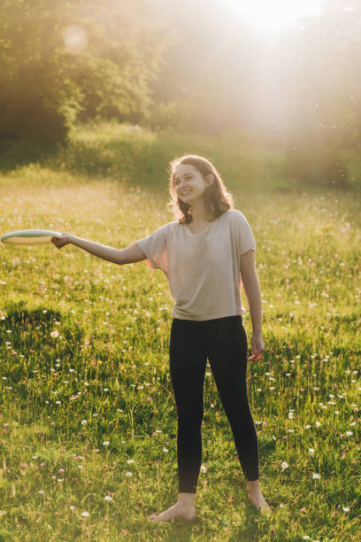 istock Woman throwing plastic disk  on the meadow at sunset 812980448