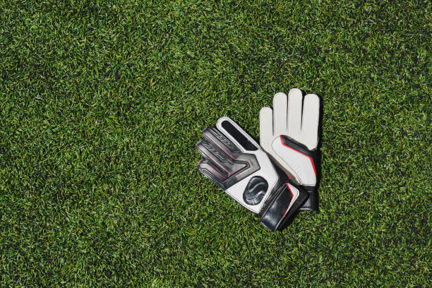 top view of goalkeeper gloves lying on soccer pitch - soccer glove imagens e fotografias de stock