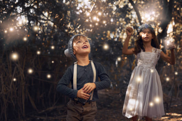 The fireflies have come out to play Shot of two little siblings catching fireflies in jars outside firefly forest stock pictures, royalty-free photos & images